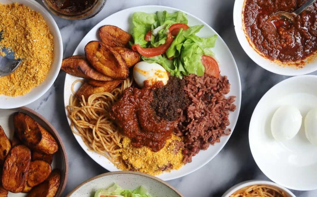 Waakye with sides — rice and beans, plantain, and stew